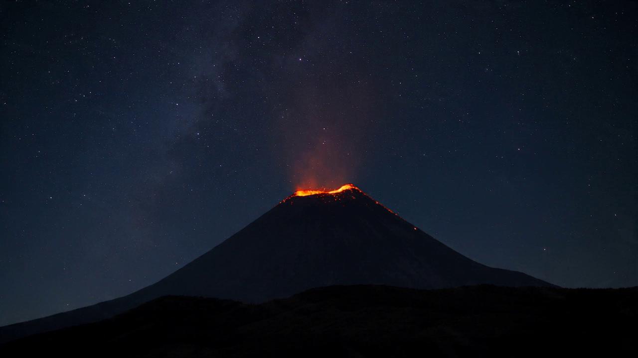 Take @video1 (first 10s: volcano flowing steadily, orange-red rim glowi…